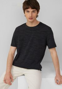 Donkergrijze t-shirt met korte mouwen, gemaakt van een gestructureerde stof, met een ronde halslijn en een ontspannen pasvorm, gecombineerd met lichtbeige broek.