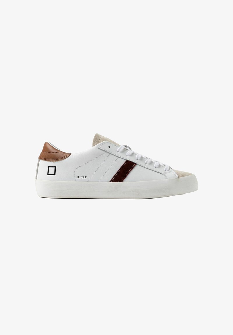 Witte leren sneaker met een bruine leren hiel en een gestructureerde beige neus. Voorzien van een bordeauxrode streep en witte veters. Rubberen zool.