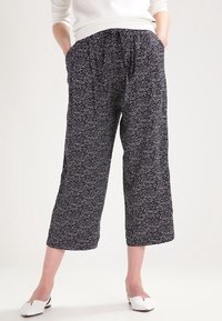 Czarne spodnie 3/4 z rozproszonym wzorem białych kropek, z elastycznym pasem i bocznymi kieszeniami, wykonane z lekkiego materiału.