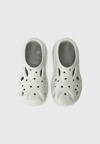 Light gray clogs made of lightweight material with multiple ventilation holes, a textured gray insole, and a curved, slip-on design.