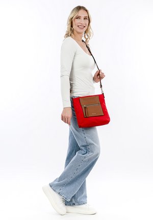 Red fabric shoulder bag with a brown leather zippered pocket, rectangular shape, adjustable strap, and smooth texture.