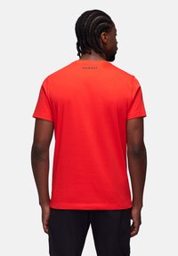 Rød bomulds t-shirt med korte ærmer, der har en rund hals og ordet "MAMMUT" i sort nær kraven, glat tekstur.