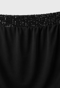 Tissu noir avec une ceinture décorée de sequins noirs brillants, montrant un contraste de textures entre un tissu lisse et des embellissements scintillants.