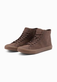 Zapatillas altas marrones de cuero con cordones planos, suela de goma, punta redondeada y detalle del logo en la parte superior.