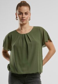 Kurzärmlige, leichte grüne Bluse mit rundem Halsauschnitt und plissiertem Vorderteil, die einen lässigen Schnitt und eine weiche Stofftextur aufweist.