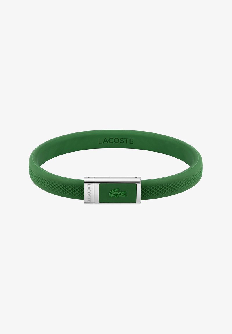 Bracelet en silicone vert avec un fermoir en argent portant un logo Lacoste en relief et des accents texturés sur le bracelet. Fini lisse sur l'ensemble.