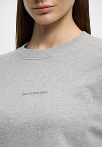 Szürke pulóver bordázott kerek nyakkal. Finom "Marc O'Polo DENIM" logóval azonos szürke árnyalatban. Puha, texturált anyag.
