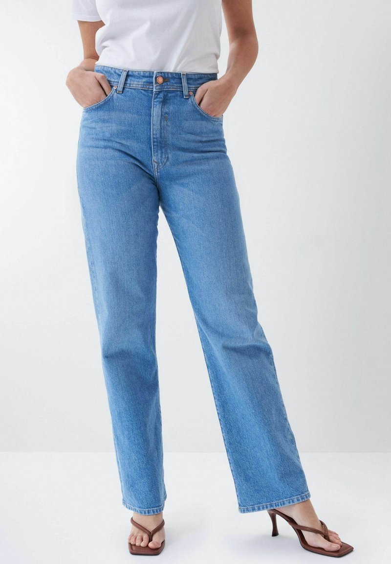 Jeans en denim bleu clair taille haute avec jambes droites amples, cinq poches et fermeture par bouton. Texture lisse et détails minimaux.