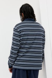 Pólo de manga longa riscado em azul marinho com riscas azuis claras e brancas. Tecido suave, colarinho e ajuste descontraído com punhos canelados.