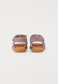 Lilla semsket sandaler med justerbar stropp, åpen hæl og brun gummisåle. Har fargerike sideaksenter og polstret såle.