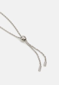 Strieborný náhrdelník so posuvným okrúhlym zapínaním, ktorý má dve tenké retiazky končiace v valcových akcentoch so malými kameňmi.