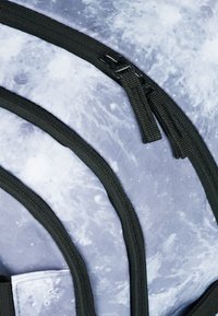 Zaino con un motivo blu e grigio simile all'acqua, dotato di cerniere e bordi neri. Tessuto texturizzato con più scomparti visibili.