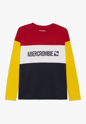 Chemise à manches longues avec un haut rouge, un panneau central blanc avec le texte "Abercrombie" et le logo de l'orignal, un bas bleu marine et des manches jaunes.