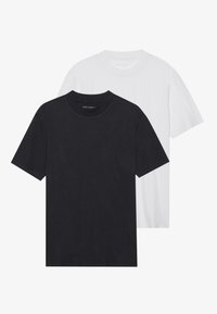 Dva majice s crew neck izrezom: jedna crna, jedna bijela. Napravljene od mekanog pamuka, s kratkim rukavima i opuštenim krojem. Nema vidljivih uzoraka ili logotipa.