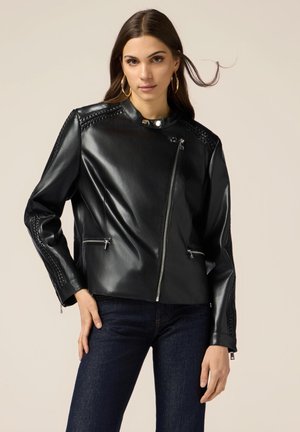 Giubbotto in pelle nera con zip diagonale, dettagli intrecciati sulle spalle, chiusura a bottoni e tasche laterali con zip. Texture liscia, design aderente.