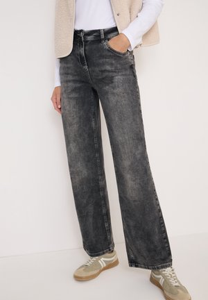 Zwarte denim jeans met wijde pijpen en een vervaagde textuur, voorzien van zijzakken en een traditionele vijfzakkenontwerp, in combinatie met grijze sneakers.