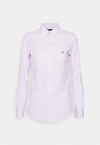 Camisa de botones de color púrpura claro hecha de algodón, con un collar clásico, mangas largas y un pequeño logo bordado. Textura suave.