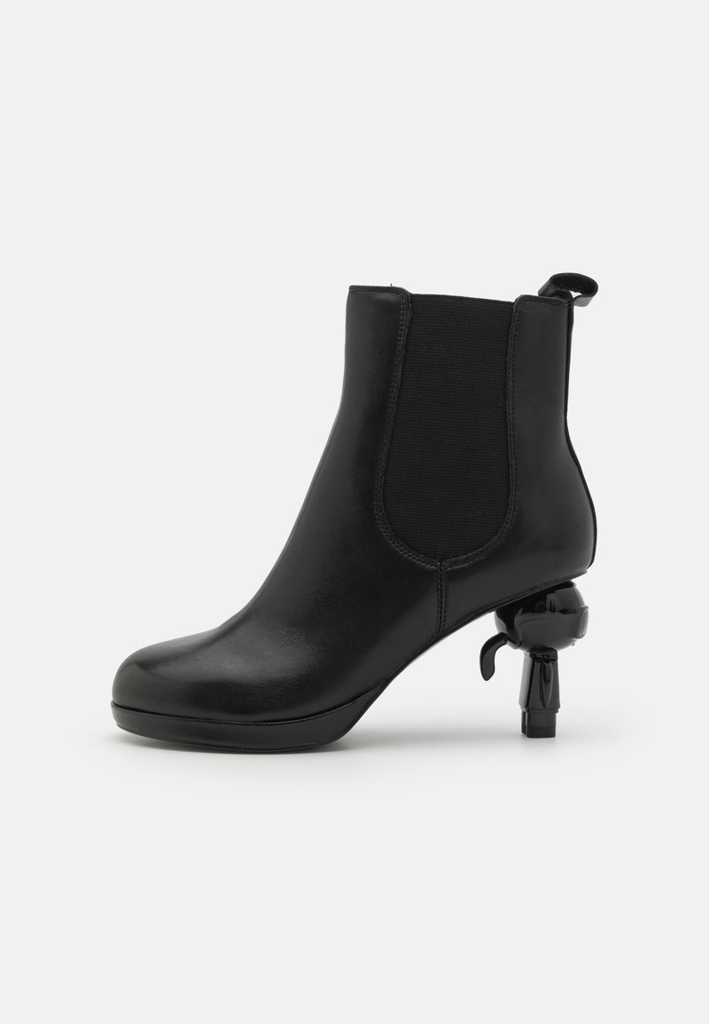 Bottine en cuir noir avec panneaux latéraux élastiques, bout arrondi et talon en forme de pistolet unique. Texture lisse et design élégant.