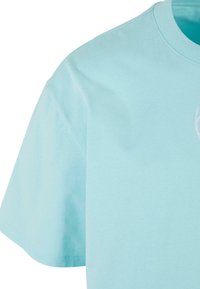 Light blue cotton t-shirt featuring a round neckline and short sleeves. Smooth texture with minimalistic design and subtle detailing.