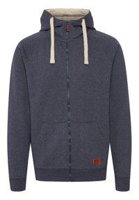 Sudadera de cremalleras gris oscuro hecha de una suave mezcla de algodón, con cordones beige, bolsillos frontales y un pequeño parche de logo en la parte inferior izquierda.