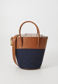 Brown leather and navy denim bucket bag with short handles, adjustable strap, and tan interior featuring a patterned lining.