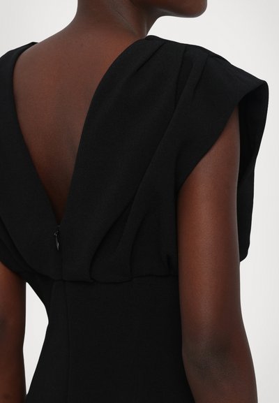Black dress featuring a deep V-back and structured shoulder design with pleats. Smooth texture and hidden zipper detail at the back.