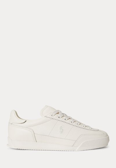 Λευκό δερμάτινο sneaker χαμηλού προφίλ με κορδόνια, υφασμένη σόλα και διακριτικό λογότυπο στο πλάι, παρουσιάζεται σε πλάγια όψη σε απλό φόντο.