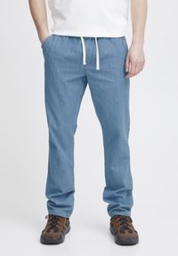 Pantalones rectos de color azul claro con una cintura elástica y cordón blanco. La tela parece suave; diseño minimalista sin patrones visibles.
