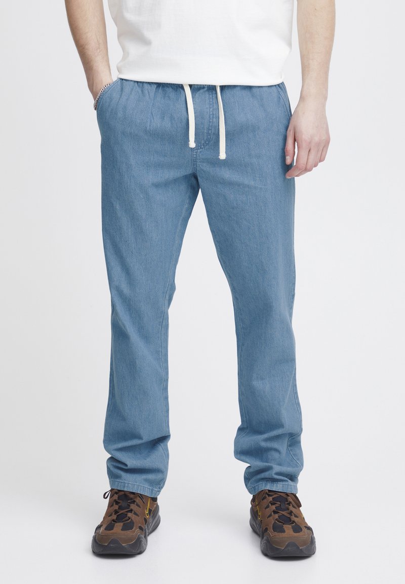 Pantalones rectos de color azul claro con una cintura elástica y cordón blanco. La tela parece suave; diseño minimalista sin patrones visibles.