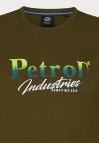 Olivově zelené bavlněné tričko s velkým gradientním textovým grafickým prvkem v modré a bílé, které uvádí "Petrol Industries" s "Hawaii Reg. 5026."