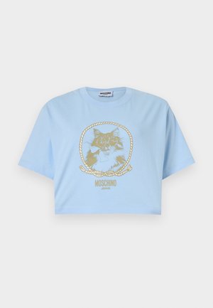 Ανοιχτό μπλε κοντομάνικο T-shirt με χρυσή απεικόνιση γάτας πλαισιωμένη από ένα σχοινί και το κείμενο «MOSCHINO JEANS» από κάτω.