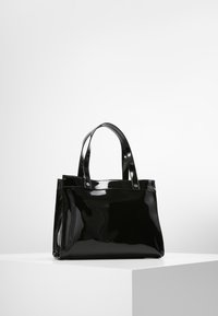 Svart lackläder tote-väska med två korta handtag, fyrkantig form, slät yta och metallaccenter vid handtagsfästen.