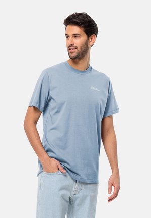 Helles blaues Baumwoll-T-Shirt mit kurzen Ärmeln und Rundhalsausschnitt. Enthält ein kleines Logo auf der Brust. Kombiniert mit hellen Jeans.
