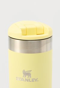 Roestvrijstalen geïsoleerde reisbeker, geel poedergecoat lichaam, zilveren metalen band, en een gele deksel met een flip-top opening.