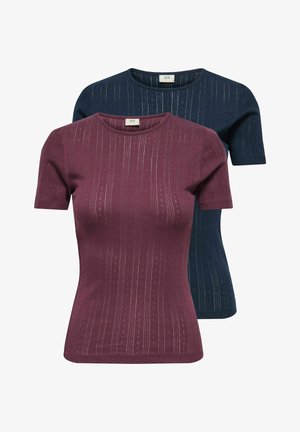 Burgunderfarbens, strukturiertes Kurzarmoberteil, kombiniert mit hellblauen, enganliegenden Jeans und maronenfarbigen Ballerinas mit einer Schleifendetail.