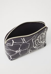 Sort kosmetisk pouch med hvidt blomstermønster, lynlås-lukning og prægede logo. Glat tekstur, rektangulær form og forstærkede syninger.