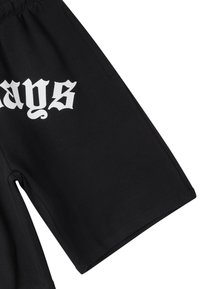 Pantaloni corti neri realizzati in un materiale morbido con una vestibilità comoda, dotati di stampa grafica bianca e tasche laterali.