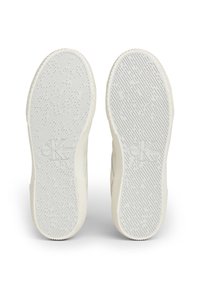 Biała podeszwa sportowego buta z teksturowanym wzorem grip, z wytłoczonym logo "Calvin Klein Jeans". Zaokrąglony kształt z delikatnymi rowkami po bokach.