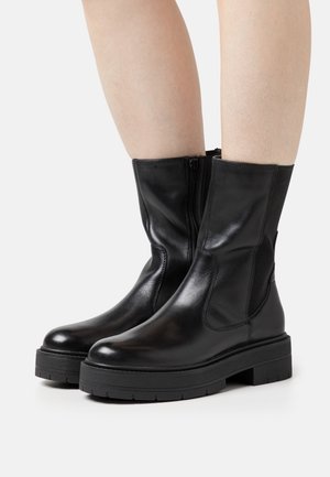 Black leather ankle boots with elastic side panels, a rounded toe, and a chunky rubber sole. Smooth texture with minimal detailing.