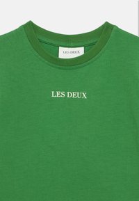 Πράσινο βαμβακερό μπλουζάκι με στρογγυλή λαιμόκοψη, με λευκό κείμενο "LES DEUX" τυπωμένο μπροστά. Ομαλή υφή και κανονική εφαρμογή.