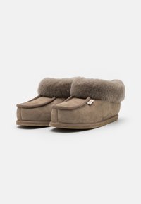 Tan suedestøvletter med en myk, grå shearling-fôr. Rund form og brettede cuff, med en teksturert såle for godt grep.
