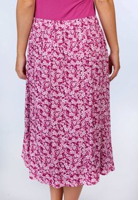 Blumen-Midi-Rock mit einem pinken Hintergrund und weißen Blumenmustern. Entworfen mit einem elastischen Taillenbund und einer fließenden Silhouette.