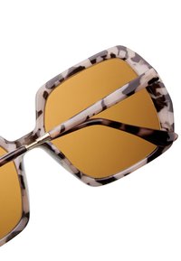  Överdimensionerade solglasögon med ett mönstrat ljusbeige och mörkbrunt bågar. Gula linser och eleganta svarta stänger med en blanka finish.