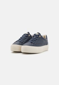 Sapatilhas de couro azul marinho com sola espessa em creme, costuras brancas e ilhós em tom dourado. Design com cadarços e pormenores minimalistas.