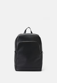 Sac à dos en cuir noir avec une texture lisse, poche frontale zippée et une poignée sur le dessus. Présente des coutures discrètes et des bords arrondis.