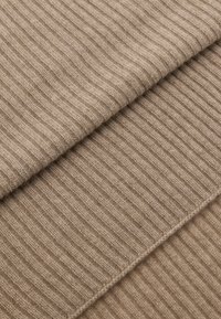 Hnědá žebrovaná tkanina, vrstvená ve třech sekcích. Měkká textura s konzistentním vzorem a různými odstíny béžové. Vhodná pro oděvy a textilie.