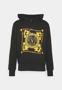 Felpa nera con cappuccio caratterizzata da una grafica gialla con motivi intricati e testo, cappuccio con coulisse e polsini e orlo a coste.