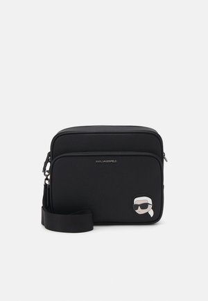 Melns sintētisks krustsoma ar gludu tekstūru, ar rāvējslēdzēju un ar karikatūras varoņa plāksteri priekšpusē. Iekļauta regulējama siksna.