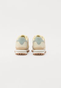 Sportsko sneakers med en myk beige og pastellblå overdel, hvit mellomsåle og teksturert brun yttersåle. Har en polstret krave og tunge.