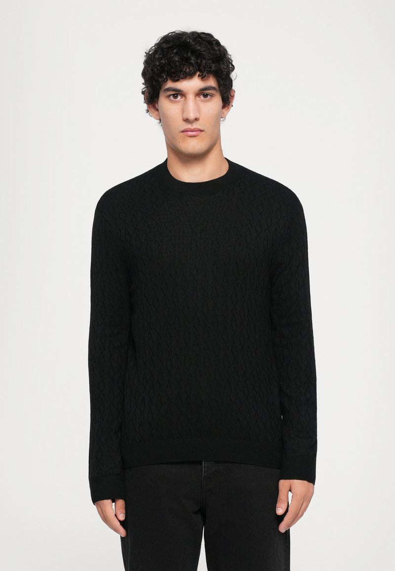 Schwarzer Strickpullover mit einem Rautenmuster, rundem Ausschnitt und gerippten Bündchen, kombiniert mit dunklen Jeans. Geeignet für legere Kleidung.